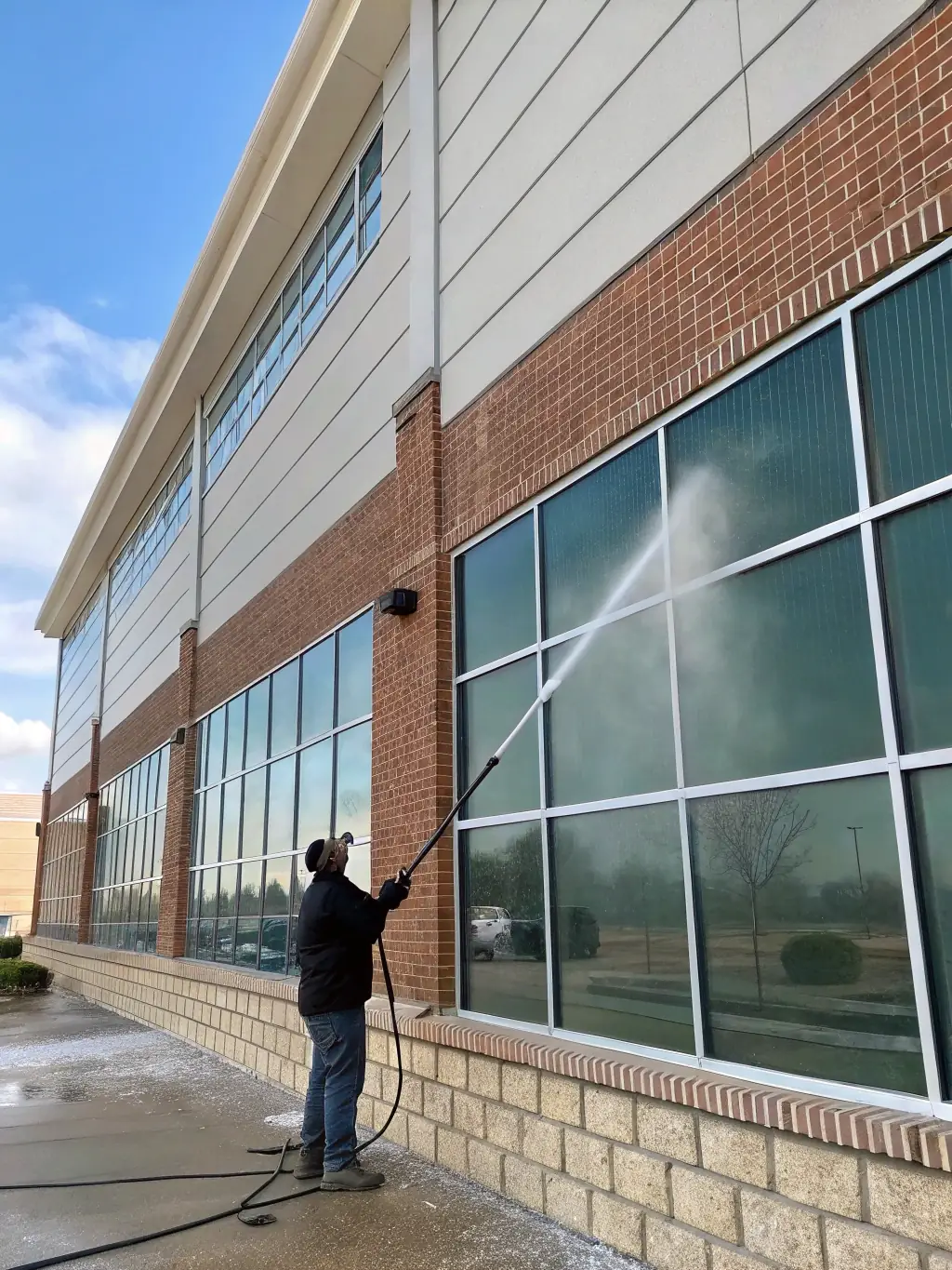 A commercial building's facade being power washed, highlighting the removal of graffiti and dirt, restoring a professional look.